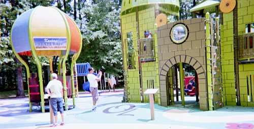 Father taking a picture of his child playing with a mobile phone.